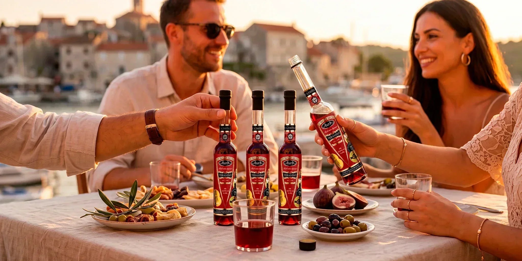 Aura Teranino mini bottle set shared by friends at a seaside dinner, styled with olives, figs and sunset light in a warm Croatian aperitivo atmosphere.