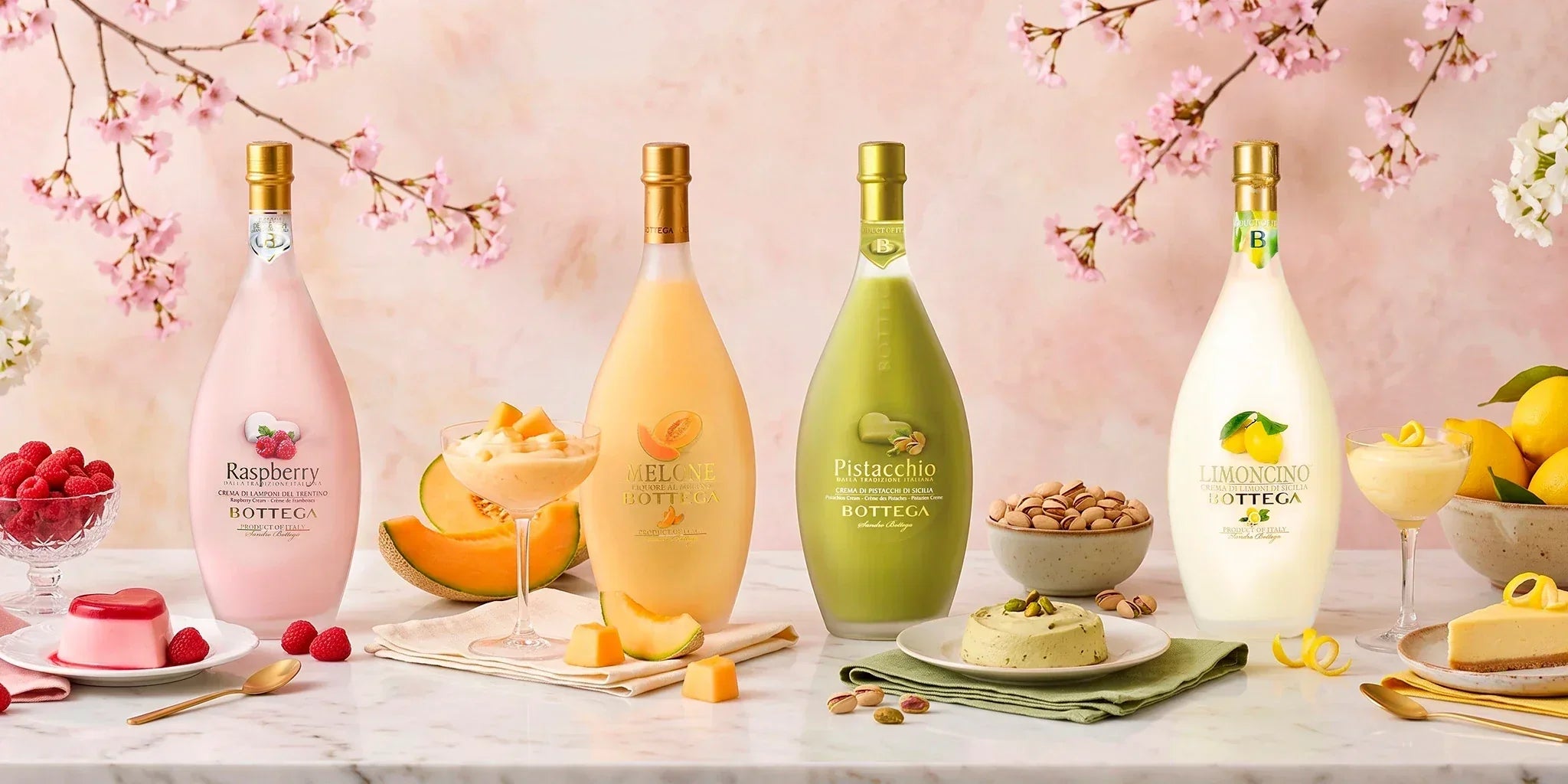 Bottega cream liqueur collection with Raspberry, Melone, Pistacchio and Limoncino bottles styled with fruit, desserts, pistachios and spring flowers.