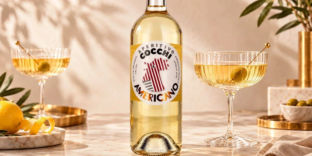 Cocchi Aperitivo Americano bottle served with elegant aperitif cocktails, green olives and lemon peel in a bright refined Italian-style setting.