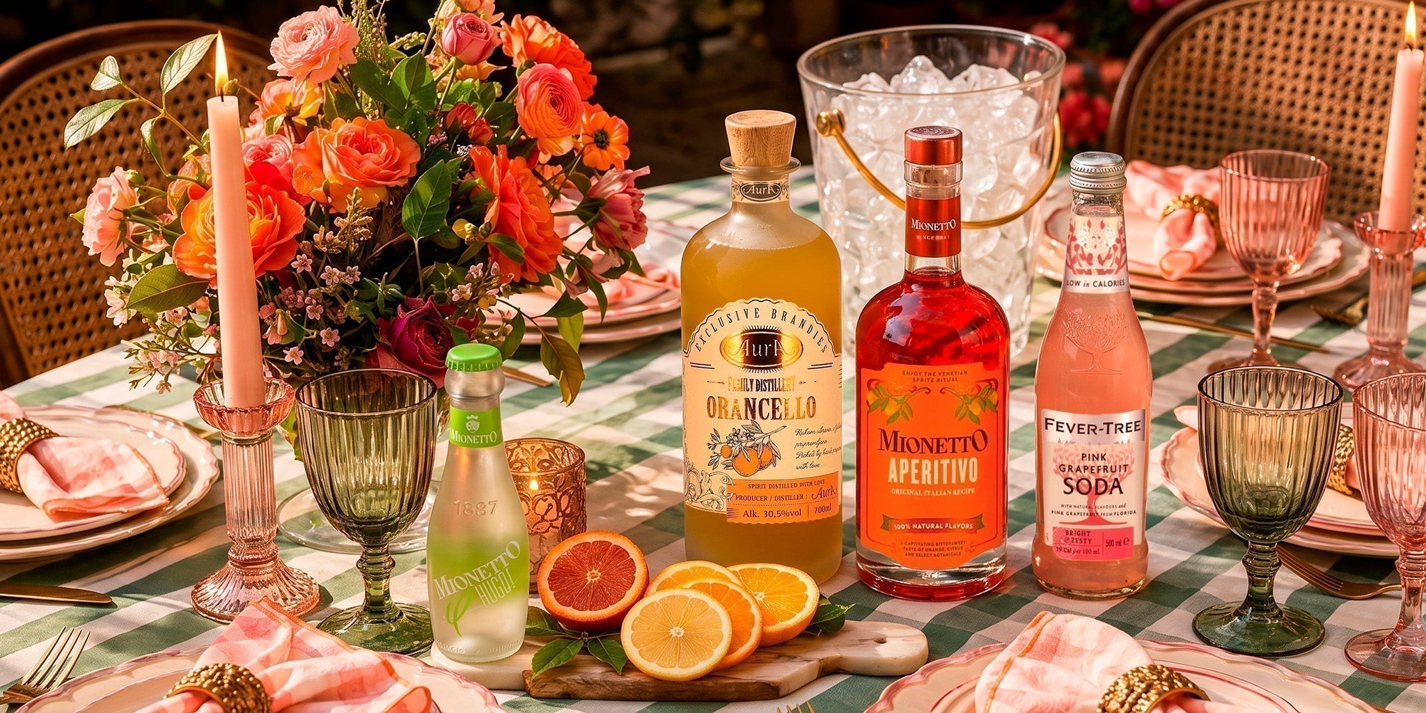 Home bar essentials with Aura Orancello, Mionetto Aperitivo, Fever-Tree Pink Grapefruit Soda and Mionetto alcohol-free sparkling wine on a colorful summer table.
