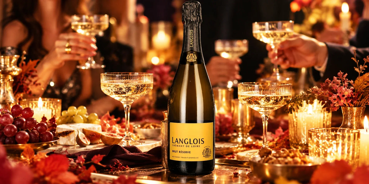 Langlois Crémant de Loire Brut Réserve 12.5% bottle served with sparkling wine in elegant coupe glasses at a warm candlelit dinner table with grapes, cheese, figs and autumn floral décor.