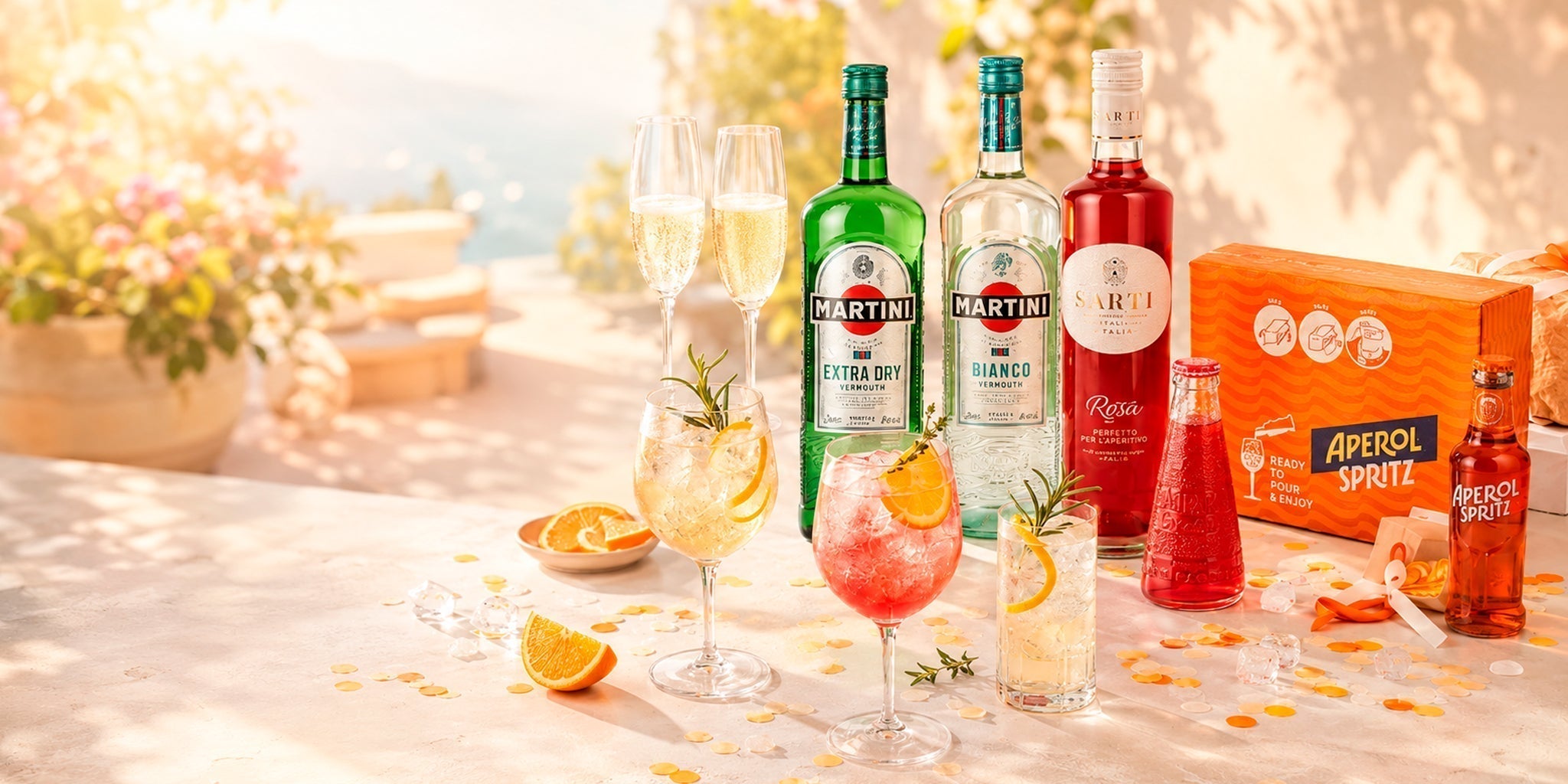 Low ABV summer cocktail setup with Martini vermouth, Sarti Rosa, Aperol Spritz bottles and light citrus highballs on a bright sunlit terrace.