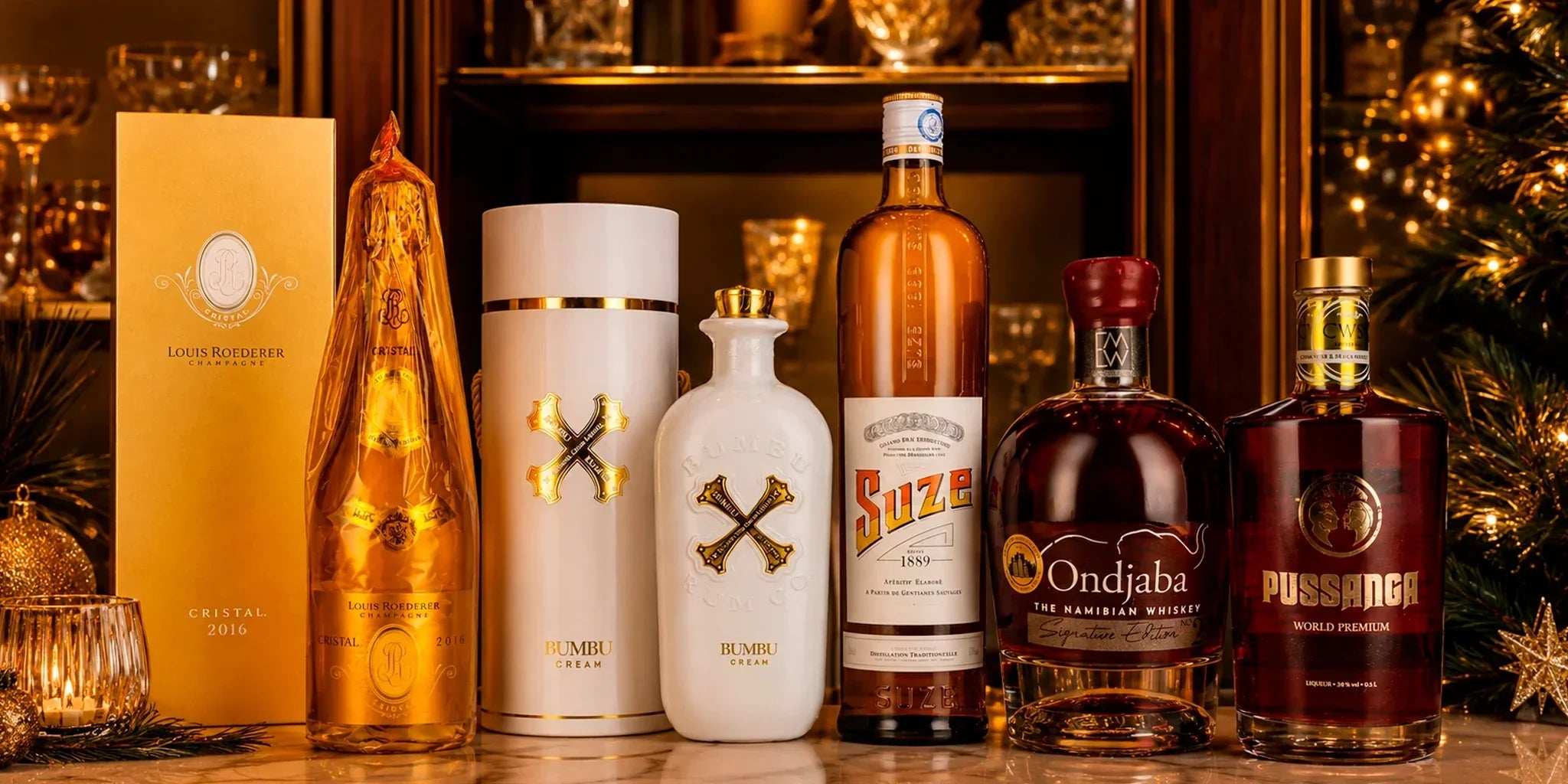 Premium home bar spirits selection featuring Louis Roederer Cristal 2016 Champagne, Bumbu Cream, Suze aperitif, Ondjaba Namibian Whiskey and Pussanga liqueur styled in a warm festive setting with glassware and holiday lights.